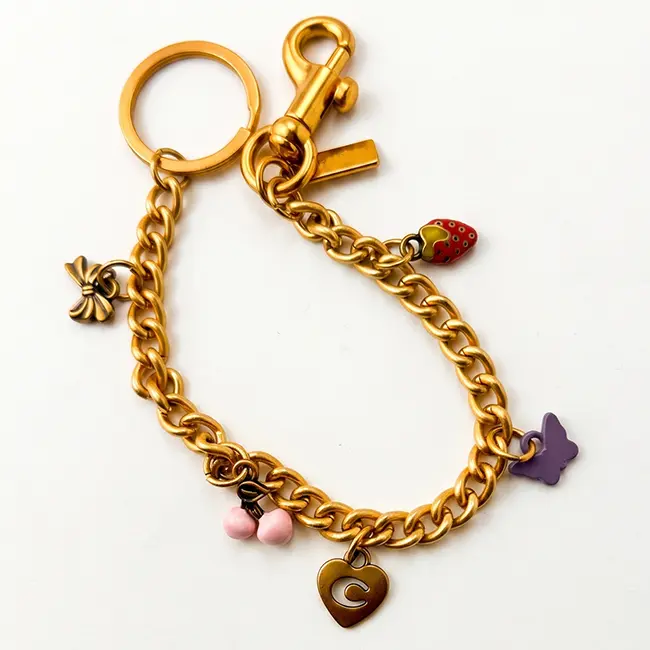 Vista principal de cadenas decorativas al por mayor en aleacion de zinc oro claro adornadas con fresa esmaltada cerezas rosa claro y lazo de bronce antiguo