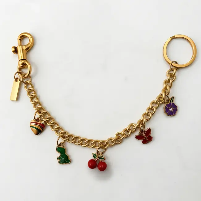 Vista principal de cadenas decorativas para bolsos al por mayor en aleacion de zinc oro claro adornada con cerezas rojas esmaltadas flor morada y mariposa