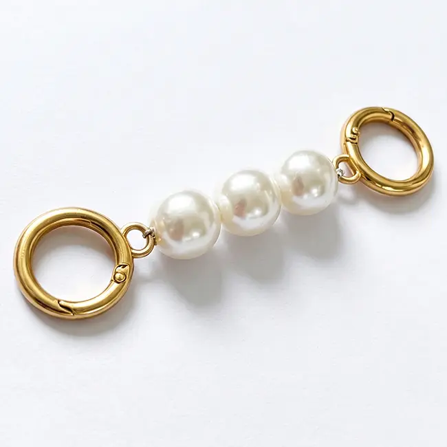 Vista principal de cadenas de perlas de imitatacion con tres perlas grandes de 18mm unidas a mosquetones de presion redondos en aleacion de zinc oro claro