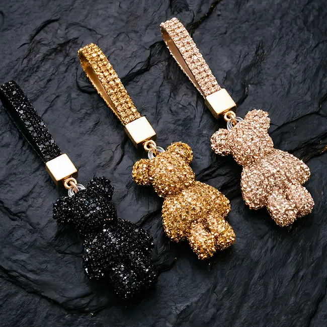 Three luxurious factory direct pavé charms displayed in jet black, yellow gold, and champagne light brown, featuring full body optical rhinestone inlaid bear motifs and robust gold zinc alloy spring snap hook closures.