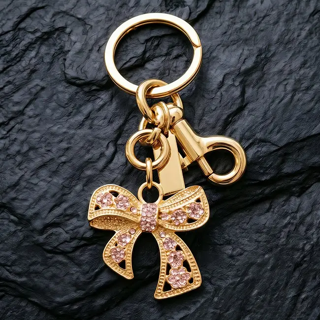 A macro material detail view of the light metallic gold hollow bow custom crystal inlaid components showcasing soft pink optical rhinestones precisely set into the floral zinc alloy ribbon latticework.