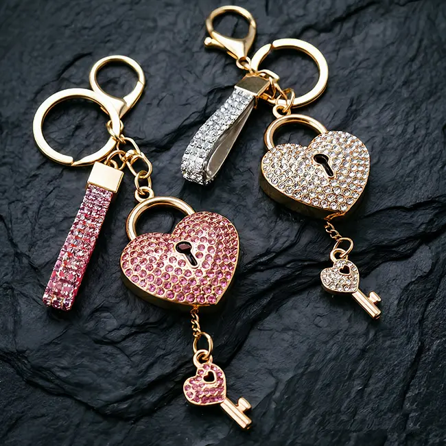 A macro material detail view of the light metallic gold heart shape lock custom pink & clear crystal inlaid components showcasing the precise rhinestone settings and miniature key dangle hardware attachments.