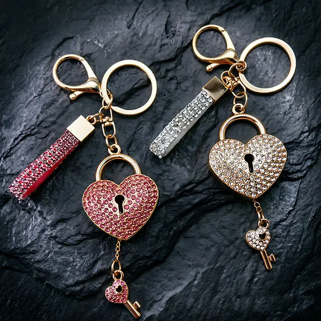 A pair of premium light metallic gold heart shape lock custom crystal inlaid components featuring vibrant pink and crystal clear optical rhinestones with matching straps on a dark slate mat.