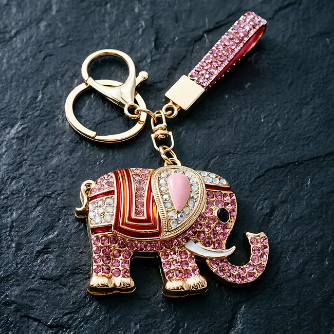 A premium light metallic gold custom crystal inlaid components accessory featuring a soft pink optical rhinestone elephant with enamel-infill details, a heavy-duty clasp, and a matching strap on slate.