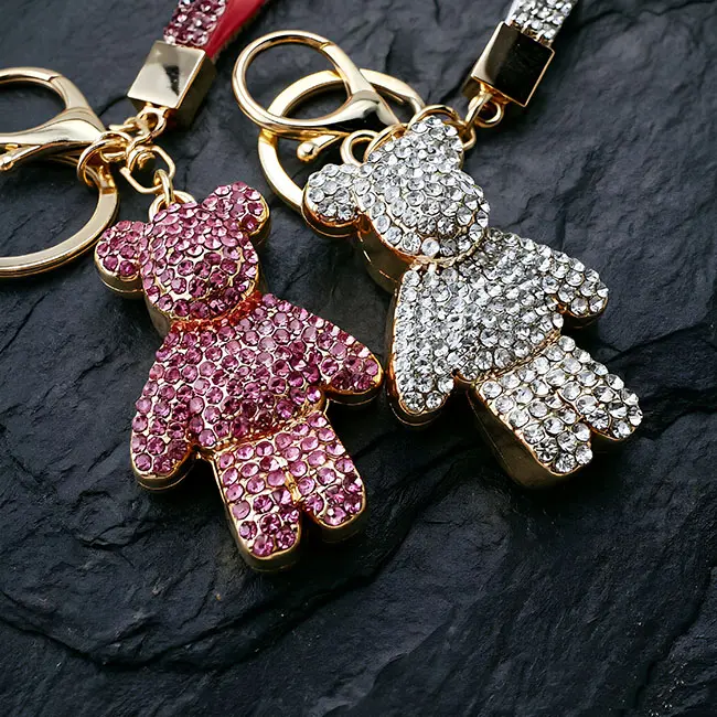 A macro material detail view of the factory direct pavé charms showcasing both the rose pink and crystal clear optical rhinestone bears, emphasizing the precise stone settings and gold finish.
