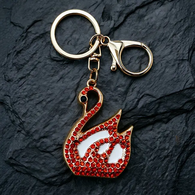 A premium B2B optical crystal molding accessory featuring a ruby red rhinestone goose charm with crisp white enamel infill on a light gold zinc alloy structure, complete with a heavy duty clasp on slate.