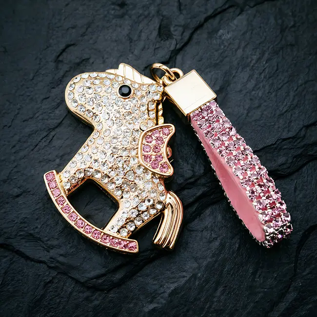 A hardware assembly close up view of the bulk crystal hardware accessory highlighting the soft pink optical rhinestone rocker horse charm and heavy duty light gold zinc alloy clasp on slate.