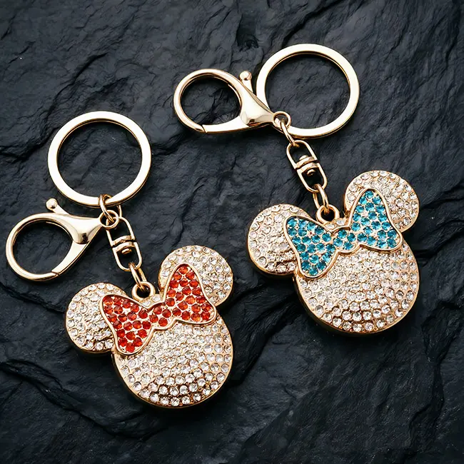 Capture attention with this pair of premium light gold B2B optical crystal molding accessories, featuring iconic mouse head charms highlighted by vibrant ruby red and teal blue rhinestone bows on a dark slate background.