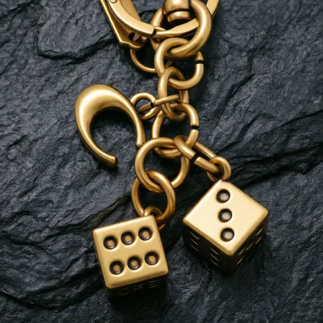 A macro material detail view of the antique finish metal casting keyrings showcasing the precision die-cast dice charms - uppercase C detail - and vintage brass plating over high-grade zinc alloy.