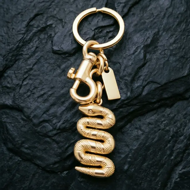 A macro material detail view of the lighter gold Precision Zinc Alloy 3D moulded charms keyring showcasing the precision die-cast snake scale textures - coiled structure - and electroplated finish.
