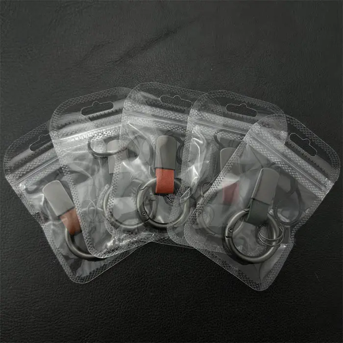 Custom metal and leather keychains packaged in clear standard OPP polybags with Euro hole punches for B2B wholesale distribution.