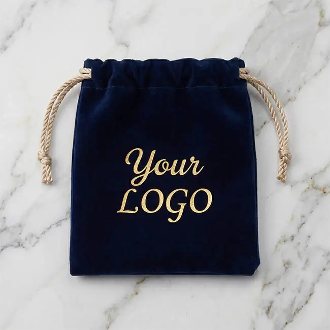 Premium dark navy velvet drawstring pouch with custom gold foil logo printing, resting on a clean marble background.